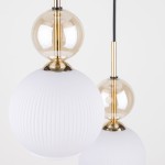 Biała lampa wisząca Sophia z trzema źródłami światła E14, z okrągłymi, matowymi kloszami w formie kul oraz przezroczystymi, szklanymi elementami w kolorze złotym. Ujęcie z przodu, z widocznymi detalami faktury kloszy.