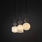 Lampa wisząca Sophia w kolorze białym z trzema kloszami o różnych kształtach: cylindrycznym, stożkowym i kulistym. Klosze mają teksturowane wykończenie, a każdy z nich jest zawieszony na czarnych przewodach. Metalowe detale w kolorze złotym.
