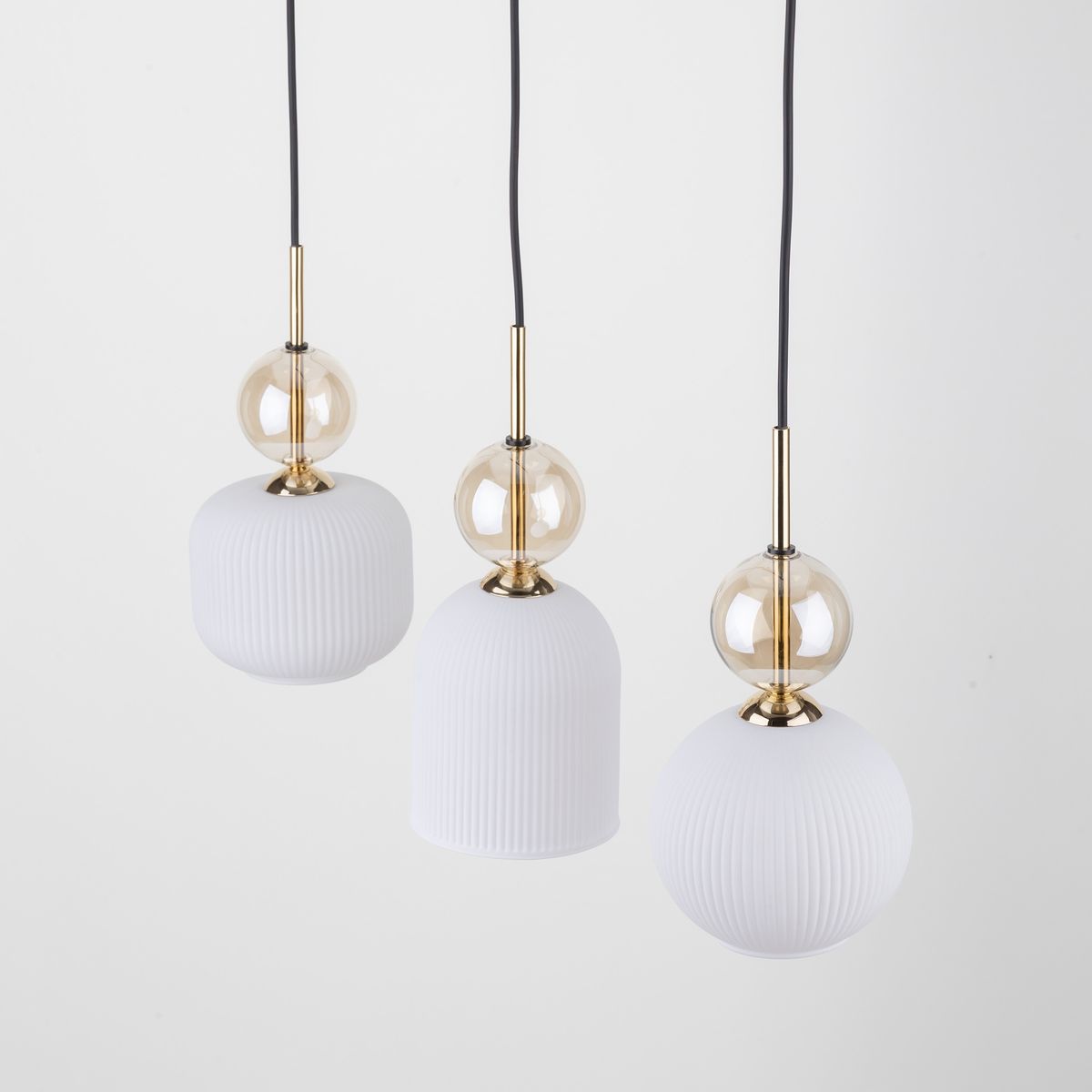 Lampa wisząca Sophia z trzema kloszami E14 w kolorze białym. Klosze mają różne kształty: cylindryczny, stożkowy i kulisty, z delikatną teksturą. Złote elementy metalowe oraz przezroczyste detale dodają elegancji. Produkt wiszący na czarnym przewodzie.
