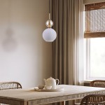 Lampa wisząca Sophia 1xE14 w kolorze białym z teksturowanym kloszem, zawieszona na cienkim czarnym przewodzie. Część metalowa w złotym kolorze, umieszczona nad okrągłym kloszem. Tło neutralne, z drewnianym stołem i filiżankami w jasnych odcieniach.