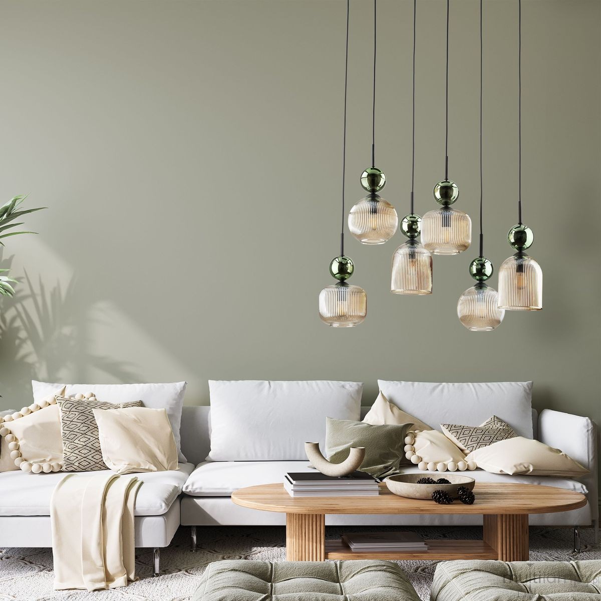 Lampa wisząca Sophia z sześcioma kloszami w kolorze bursztynowym i zielonym, zawieszona na czarnych przewodach. Klosze mają fakturę w pionowe prążki. Produkt umieszczony nad sofą w jasnym wnętrzu z roślinami i drewnianym stolikiem.