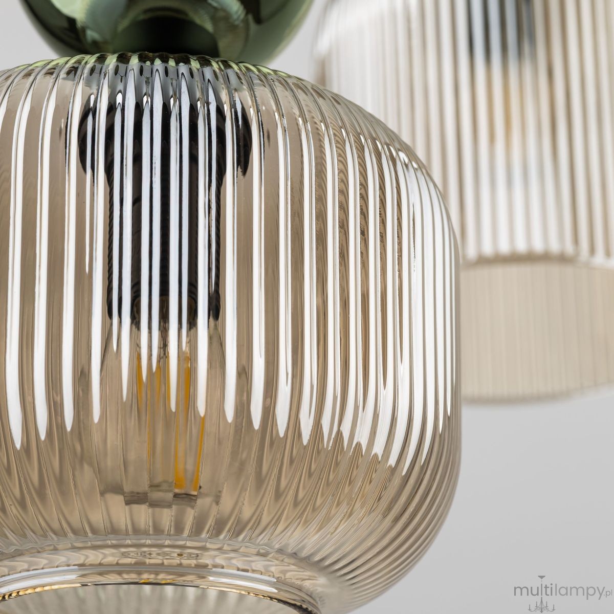 Lampa wisząca Sophia z sześcioma oprawami E14, w bursztynowym szkle z pionowymi żłobieniami, z zielonym elementem mocującym. Widok zbliżony na szklane klosze, ukazujący detale tekstury i kształtu.