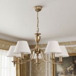 Złoty żyrandol 5-punktowy Sofia z białymi kloszami, zawieszony na łańcuchu. Klosze mają kształt stożków, a całość utrzymana jest w eleganckim stylu. W tle widoczna dekoracyjna tapeta.