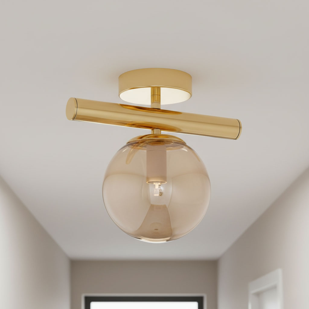 Złota lampa sufitowa 1-punktowa Eral z przezroczystą, szklaną kulą o delikatnym odcieniu. Utrzymana w minimalistycznym stylu, montowana do sufitu, z prostym, poziomym uchwytem. Idealna do nowoczesnych wnętrz.