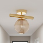 Złota lampa sufitowa 1-punktowa Eral z przezroczystą, szklaną kulą o delikatnym odcieniu. Utrzymana w minimalistycznym stylu, montowana do sufitu, z prostym, poziomym uchwytem. Idealna do nowoczesnych wnętrz.