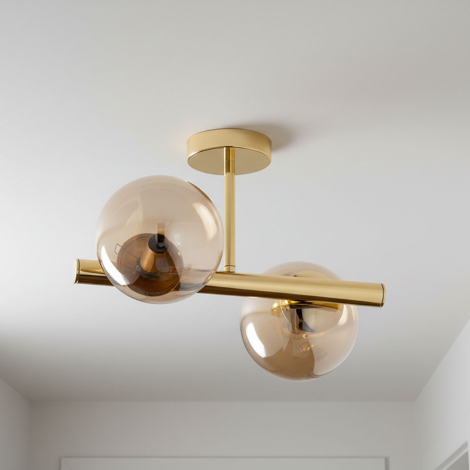 Lampa sufitowa Eral 2-punktowa w kolorze złotym z przezroczystymi kloszami. Ułożona poziomo, z dwoma okrągłymi, lekko przydymionymi szklanymi kulami na metalowym ramieniu. Montowana do sufitu, elegancki design z minimalistycznym wykończeniem.