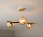 Lampa sufitowa Eral 3-punktowa w złotym kolorze z transparentnymi kloszami. Zawieszona na metalowej rurze, posiada trzy okrągłe źródła światła. Ujęcie z góry, ukazujące elegancki design i detale wykończenia.