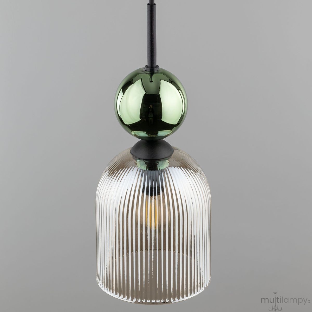 Lampa wisząca Sophia z kloszem w bursztynowym kolorze, z pionowymi żłobieniami. U góry znajduje się zielona, połyskująca kula, całość zawieszona na czarnym kablu. Produkt wisi w pozycji pionowej na szarym tle.