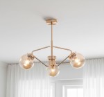 Lampa wisząca Barsum 3-punktowa w złotym kolorze z trzema przezroczystymi kloszami. Ujęcie z dołu, produkt zamontowany pod sufitem, z metalową konstrukcją. Klosze mają okrągły kształt, przezroczyste szkło, w środku widoczne źródła światła.