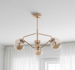 Lampa wisząca Barsum w kolorze złotym, 3-punktowa, z przezroczystymi kulistymi kloszami. Ujęcie z dołu, pokazujące całą konstrukcję oraz detale mocowania do sufitu. Prosta aranżacja w tle z białymi zasłonami.