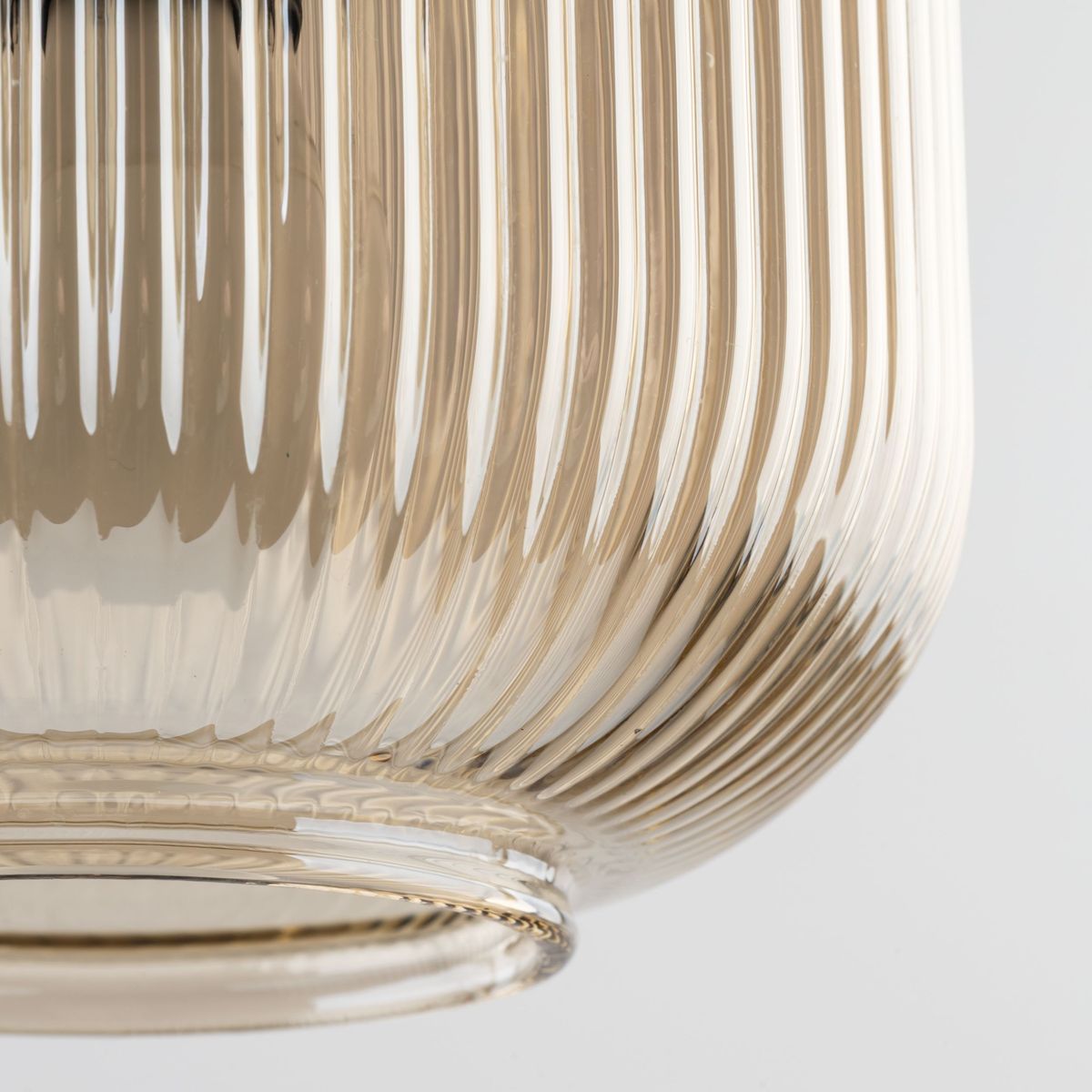 Lampa wisząca Sophia 1xE14 w bursztynowym kolorze z przezroczystego, żebrowanego szkła. Ujęcie w zbliżeniu na dolną część klosza, ukazujące jego teksturę i kształt. Idealna do nowoczesnych wnętrz.