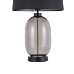 Lampa stołowa Amur 1xE27 LP-919/1T w kolorze dymnym, z okrągłym szklanym kloszem i złotą dekoracją w środku. Podstawa z czarnego metalu, abażur w kolorze czarnym. Ujęcie frontalne, stojąca na stole.