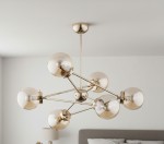 Lampa wisząca Resto 6-punktowa w kolorze złotym. Posiada sześć przezroczystych kloszy w kształcie kul, umieszczonych na cienkich metalowych ramionach rozchodzących się od centralnej części. Lampa zawieszona na długim stelażu.