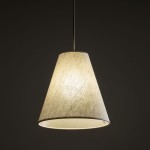 Beżowa lampa wisząca Coena Sabia z kloszem w kształcie stożka, zawieszona na cienkim przewodzie. Klosz wykonany z materiału, emituje miękkie światło. Ujęcie frontalne, na ciemnym tle, podkreślające teksturę i formę lampy.