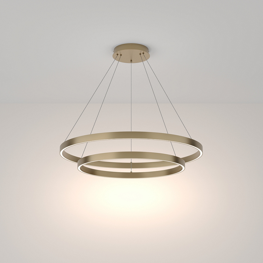 Lampa wisząca Rim 4000K, 2-punktowa, z mosiądzu, z dwoma okrągłymi pierścieniami. Zawieszona na cienkich linkach, emitująca ciepłe światło. Prosty, nowoczesny design na jasnym tle.