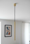 Lampa wisząca Collet 1-punktowa w kolorze złotym, o prostym, cylindrycznym kształcie, zawieszona na czarnym przewodzie. Ujęcie frontalne, ukazujące detal lampy w nowoczesnym wnętrzu. Tło neutralne, z fragmentem ściany i obrazem w ramie.