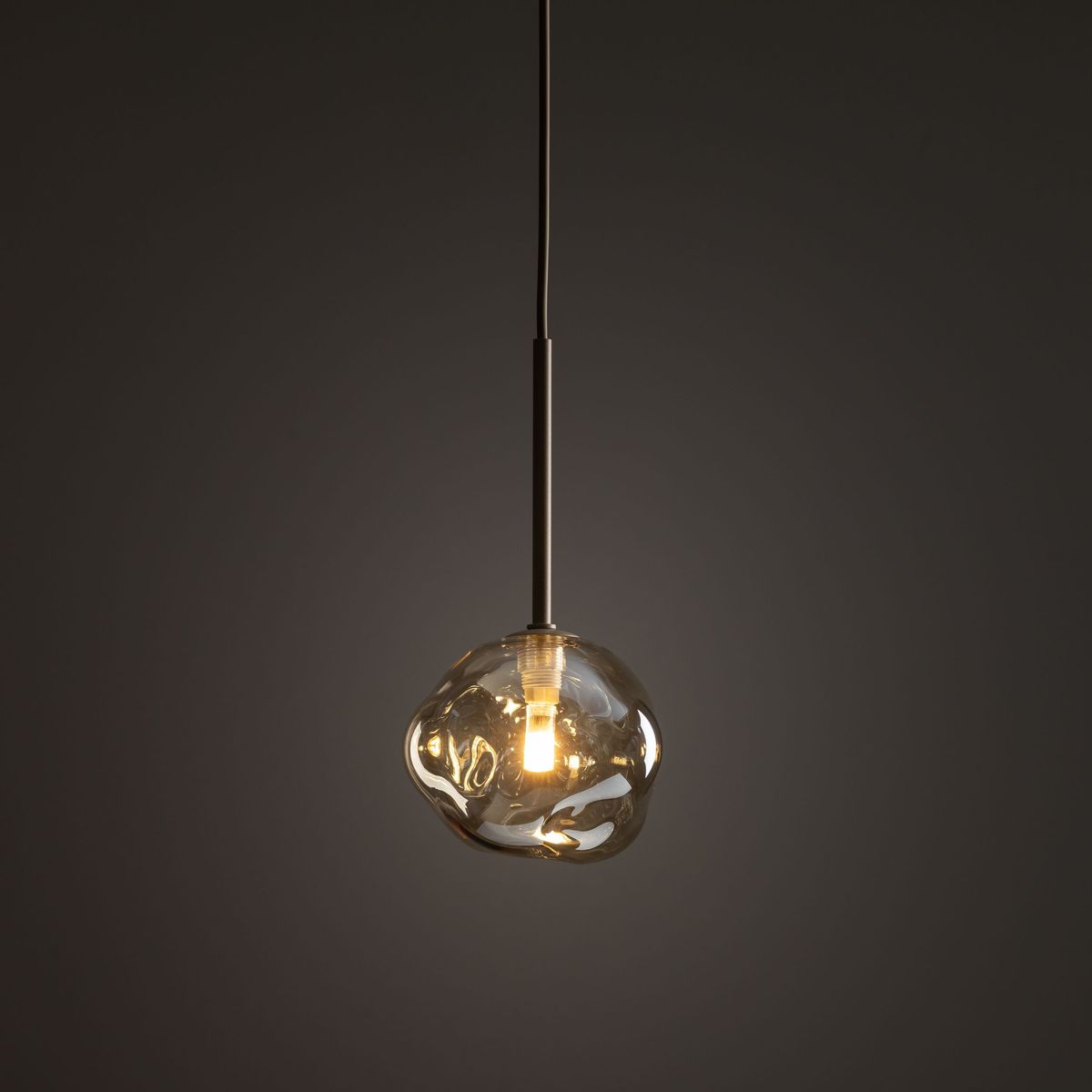Beżowa lampa wisząca Lava Sabia z pojedynczym gniazdem G9, o organicznym kształcie przypominającym kroplę. Wisi na cienkim kablu w minimalistycznym stylu, z przezroczystym kloszem, który subtelnie rozprasza światło.