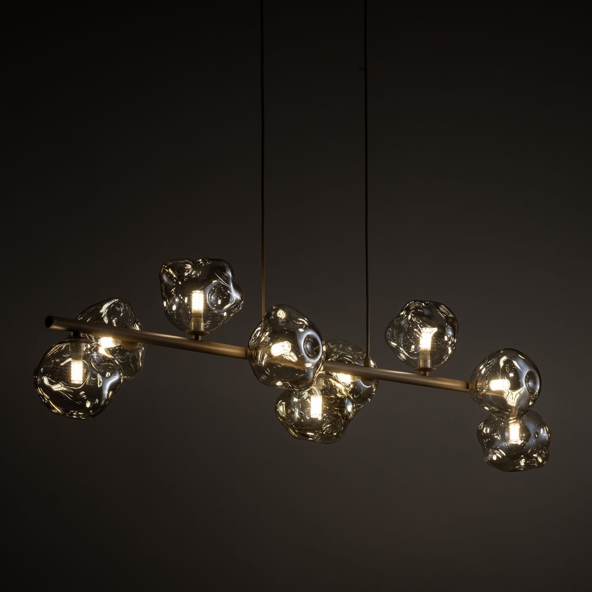 Lava Sabia lampa wisząca 9xG9 w kolorze beżowym, z metalowym stelażem, z ośmioma szklanymi kloszami o organicznym kształcie. Lampa zawieszona na cienkich linkach, emitująca ciepłe światło, idealna do nowoczesnych wnętrz.
