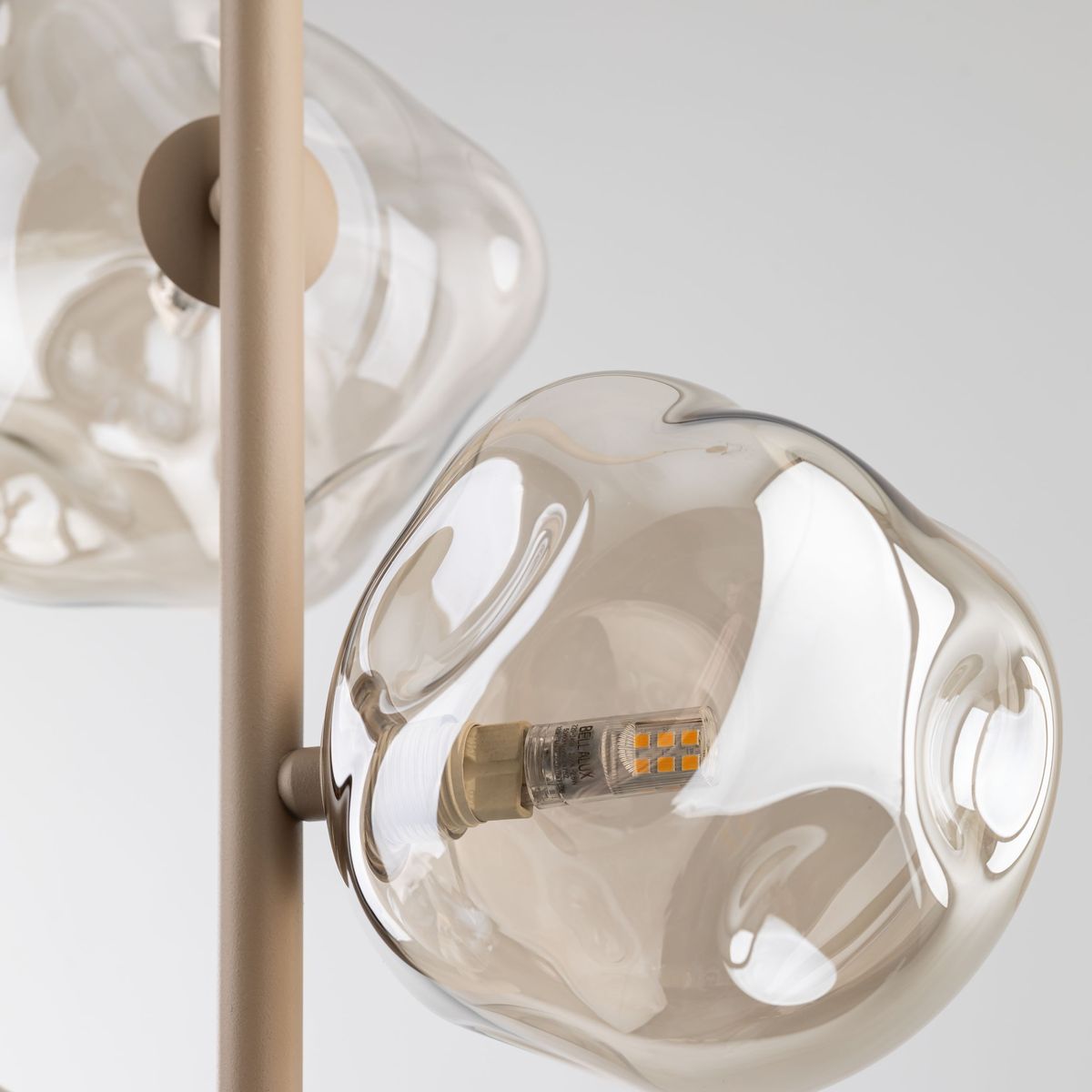 Beżowa lampa wisząca Lava Sabia z trzema źródłami światła G9. Klosze o organicznych kształtach w kolorze przezroczystym, z widocznymi diodami LED. Ujęcie z góry, ukazujące detale kloszy i mocowania.