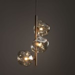 Lava Sabia lampa wisząca 3xG9 w kolorze beżowym, z trzema szklanymi kloszami w organicznych kształtach, zamontowana na cienkim, metalowym stelażu. Źródła światła G9 widoczne przez klosze, zawieszona na długim przewodzie. Tło ciemne.