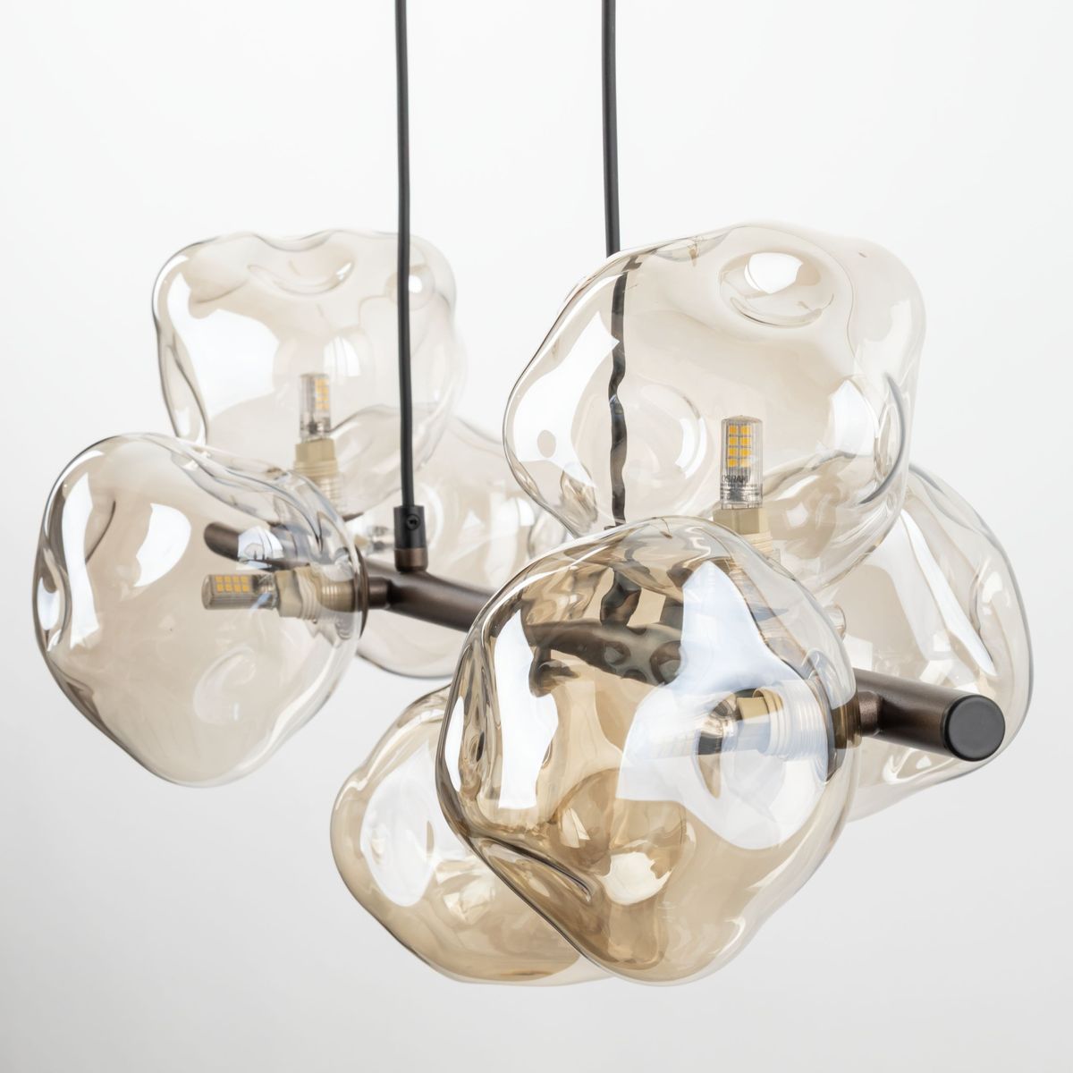 Lava Brown lampa wisząca z siedmioma kloszami G9, w kolorze brązowym. Klosze o organicznych kształtach wykonane z przezroczystego szkła, zawieszone na ciemnej metalowej konstrukcji. Lampa prezentuje nowoczesny design.