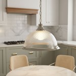 Lampa wisząca American Diner 1-punktowa w antycznym mosiądzu z kloszem w kształcie kopuły, z wyraźnym, żebrowanym wzorem. Zawieszona na łańcuszku, oświetla stół w nowoczesnej kuchni z zielonymi szafkami i marmurowym blatem.