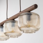 Lampa wisząca Salvia Brown z trzema kloszami E14, w kolorze brązowym. Klosze o zaokrąglonym kształcie, teksturowanej powierzchni, zawieszone na drewnianym stelażu. W tle jasne, neutralne tło.
