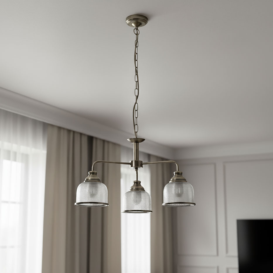 Lampa wisząca Bistro II w kolorze antycznego mosiądzu, z trzema szklanymi kloszami, zawieszona na łańcuchu. Klosze mają teksturowaną powierzchnię i metalowe obręcze. Produkt umieszczony w jasnym wnętrzu z zasłonami.