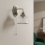 Kinkiet Bistro II w antycznym mosiądzu z przezroczystym kloszem o drobnej siatce. Montowany na ścianie, z widocznym przełącznikiem. Oświetlenie idealne do nowoczesnych i klasycznych wnętrz. Tło w neutralnym odcieniu.