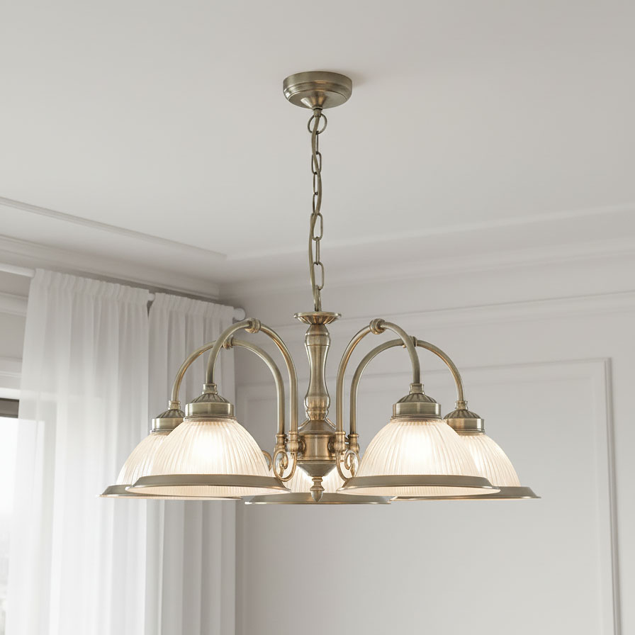 Lampa wisząca American Diner 5-punktowa w antycznym mosiądzu, z pięcioma kloszami w kształcie misek. Klosze mają fakturę, a konstrukcja lampy jest ozdobna, z widocznym łańcuchem. Zawieszona w jasnym wnętrzu.