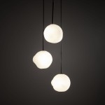 Lampa wisząca Misty z trzema kulistymi kloszami w kolorze białym, zawieszona na czarnych linkach. Klosze mają organiczny kształt, co nadaje lampie nowoczesny charakter. Tło jest ciemne, co podkreśla efekt świetlny.