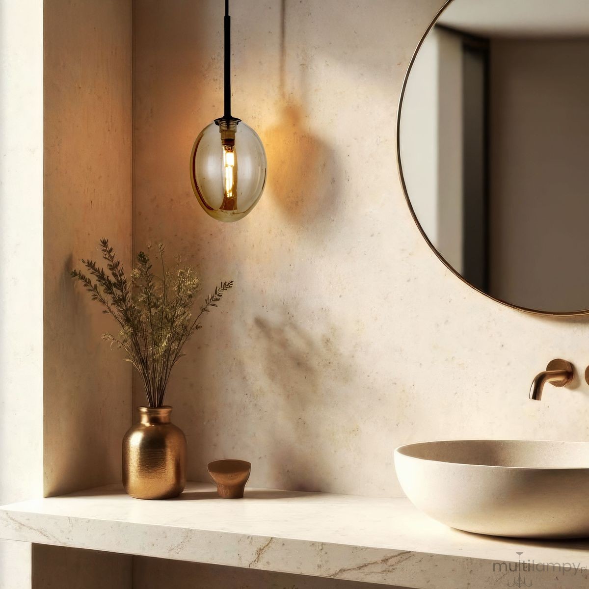 Czarna lampa wisząca Pearl Cognac z bursztynowym kloszem o owalnym kształcie, zawieszona na cienkim kablu, w eleganckim wnętrzu z lustrem i ceramiczną umywalką. W tle widoczny złoty wazon z suszonymi kwiatami.