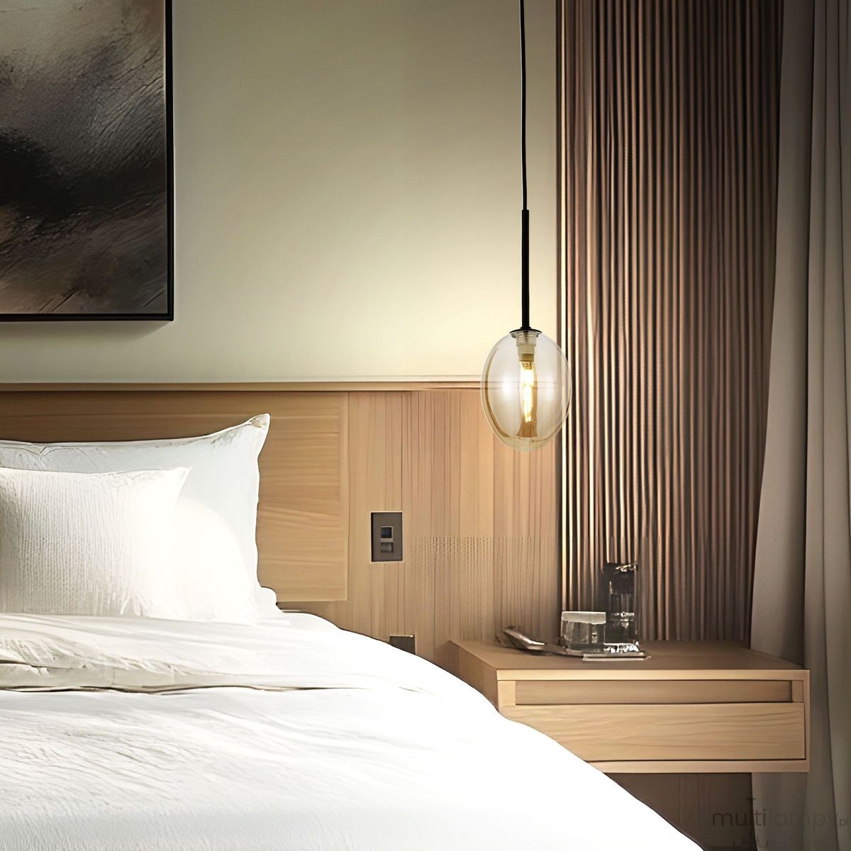 Lampa wisząca Pearl Cognac z czarnym kablem i bursztynowym kloszem, zawieszona nad łóżkiem w nowoczesnej sypialni. Klosz ma owalny kształt, a w tle widoczne są drewniane panele i stół nocny z dekoracjami.