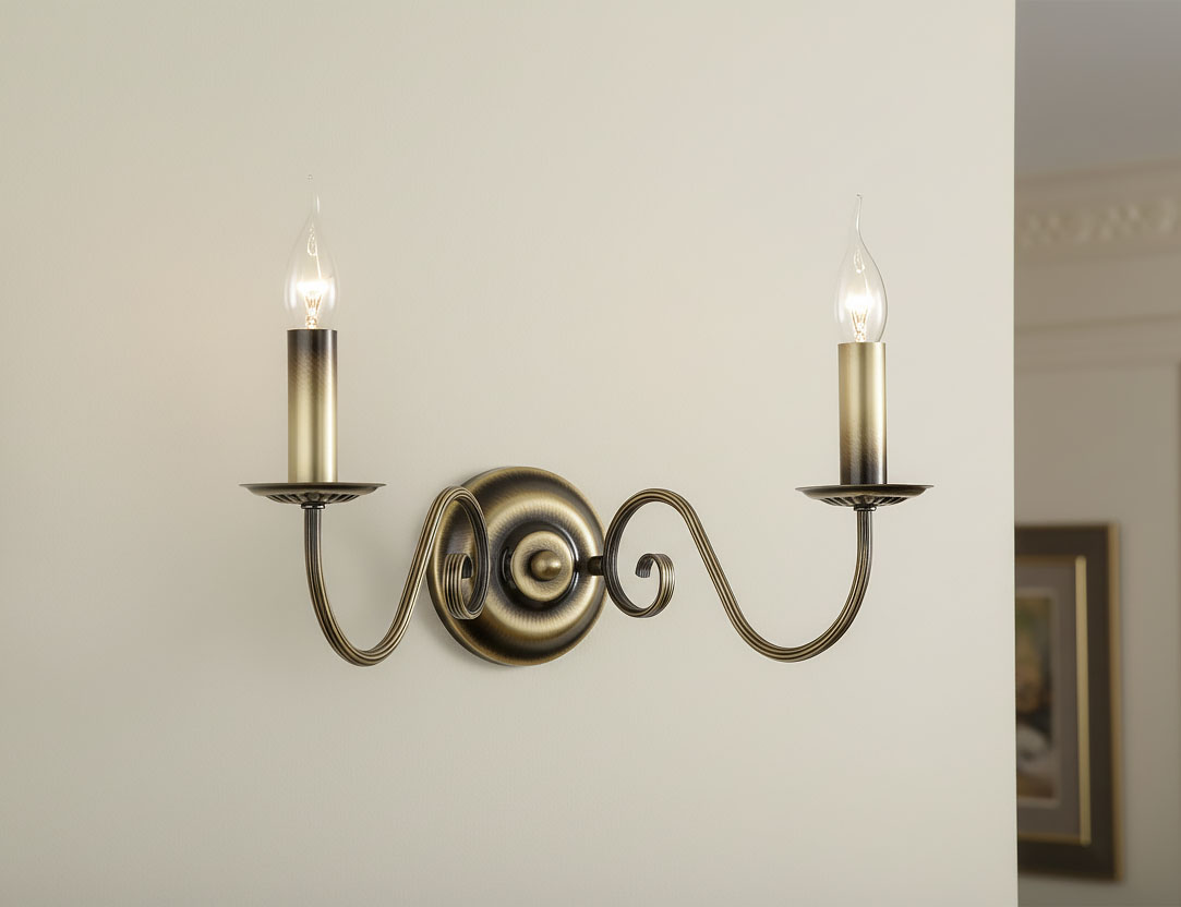 Kinkiet Asti 2-punktowy w kolorze patyny, montowany na ścianie. Posiada dwa świecznikowe ramiona z delikatnymi, szklanymi kloszami w kształcie łezki. Ozdobna, spiralna podstawa z metalowym wykończeniem.