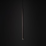 Brązowa lampa wisząca Tracer Brown 1xG9 do szyny, w formie długiego, prostokątnego tubusu. Ujęcie frontalne, lampa zawieszona na cienkim przewodzie, emitująca delikatne światło z dolnej części. Tło ciemne, podkreślające elegancki design.