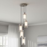 Lampa wisząca Duo I z pięcioma punktami świetlnymi w srebrnej satynie i przezroczystym kloszu. Ułożona w pionie, zawieszona na cienkich linkach. Klasyczny design, idealna do nowoczesnych wnętrz. Tło w jasnym kolorze, z lekkimi zasłonami w tle.