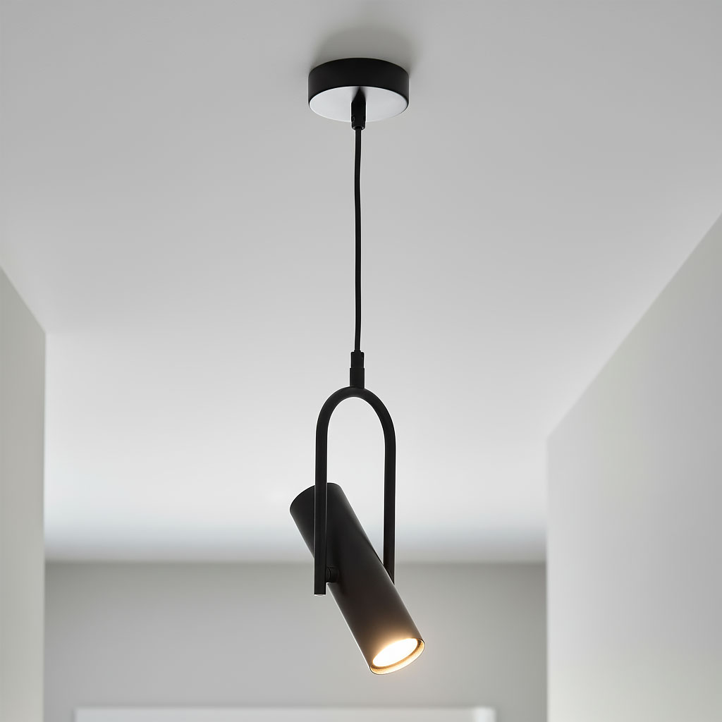 Lampa wisząca Telescope 1-punktowa w kolorze czarnym, o cylindrycznym kształcie, zawieszona na cienkim przewodzie. Ujęcie z góry, ukazujące lampa włączoną, emitującą światło, na tle jasnego sufitu.