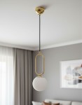 Lampa wisząca Vavil D150 w kolorze złotym i białym, z okrągłym kloszem z matowego szkła. Zawieszona na czarnym przewodzie, z metalowym elementem w kształcie owalnym. Ujęcie z dołu, w jasnym wnętrzu z zasłonami.