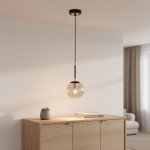 Lampa wisząca Sebia 1-punktowa 61081 z przezroczystym, szklanym kloszem w kształcie kuli, zawieszona na czarnym przewodzie. Widoczna w minimalistycznym wnętrzu na tle jasnej ściany i drewnianego mebla.