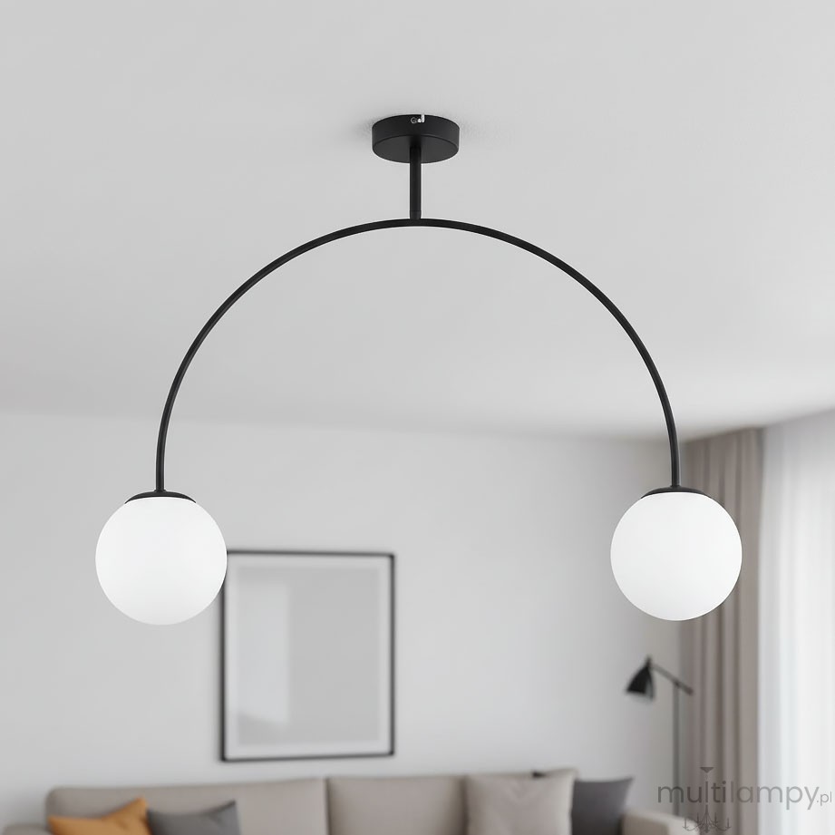 Czarna lampa wisząca Bendo z dwoma kulistymi kloszami w białym kolorze. Ułożona w łuk, zawieszona na czarnym stelażu. Widoczna w nowoczesnym wnętrzu, na tle jasnej ściany i szarej kanapy.
