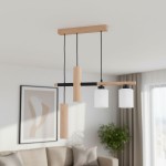 Lampa wisząca Nimir z drewna naturalnego, z dwoma szklanymi kloszami w kolorze białym i czarną metalową konstrukcją. Ujęcie z dołu, wisi na trzech linkach. Tło w jasnym wnętrzu z kanapą i dekoracjami.