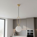 Lampa wisząca Vavil D200 w złotym kolorze z białym kloszem w kształcie kuli, zawieszona na czarnym przewodzie. Widok z góry, w nowoczesnej kuchni z szarym tłem i blatem.