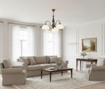 Żyrandol Felix 3xE27 w kolorze patyny, zawieszony w jasnym wnętrzu. Oświetlenie składa się z trzech mlecznych kloszy. W tle widoczny salon z beżową sofą, stolikiem kawowym i obrazem na ścianie.