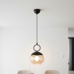 Lampa wisząca Sitro 20 w kolorze czarnym z bursztynowym kloszem, zawieszona na czarnym przewodzie. Okrągły metalowy uchwyt u góry. Źródło światła E27 widoczne wewnątrz klosza. Prosta, nowoczesna forma, idealna do wnętrz.