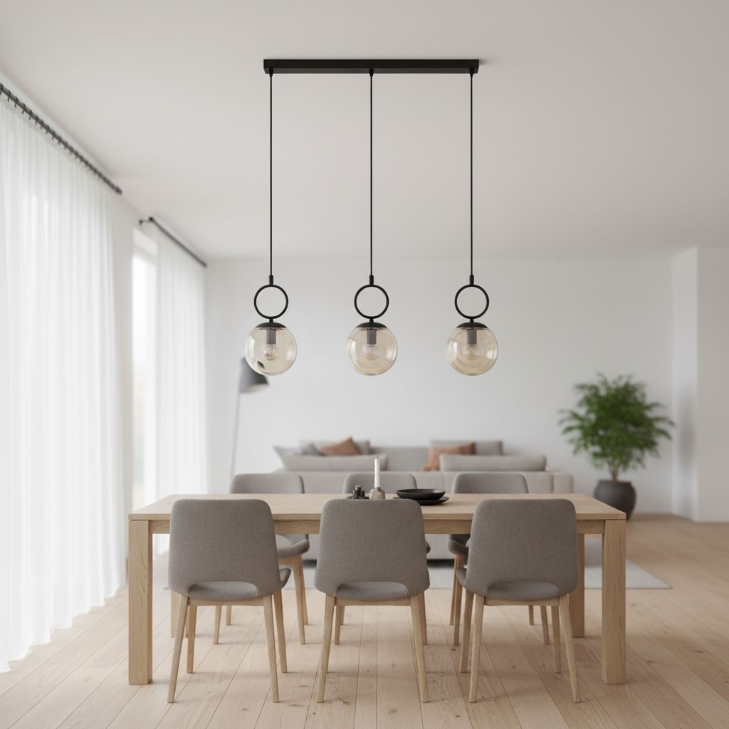 Lampa wisząca Sitro z trzema żarówkami E14 w czarnej oprawie, z bursztynowymi kloszami. Zawieszona na długich linkach, umieszczona nad drewnianym stołem, w nowoczesnym wnętrzu z jasnymi zasłonami i rośliną w tle.