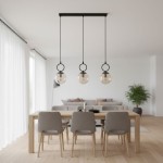 Lampa wisząca Sitro z trzema żarówkami E14 w czarnej oprawie, z bursztynowymi kloszami. Zawieszona na długich linkach, umieszczona nad drewnianym stołem, w nowoczesnym wnętrzu z jasnymi zasłonami i rośliną w tle.