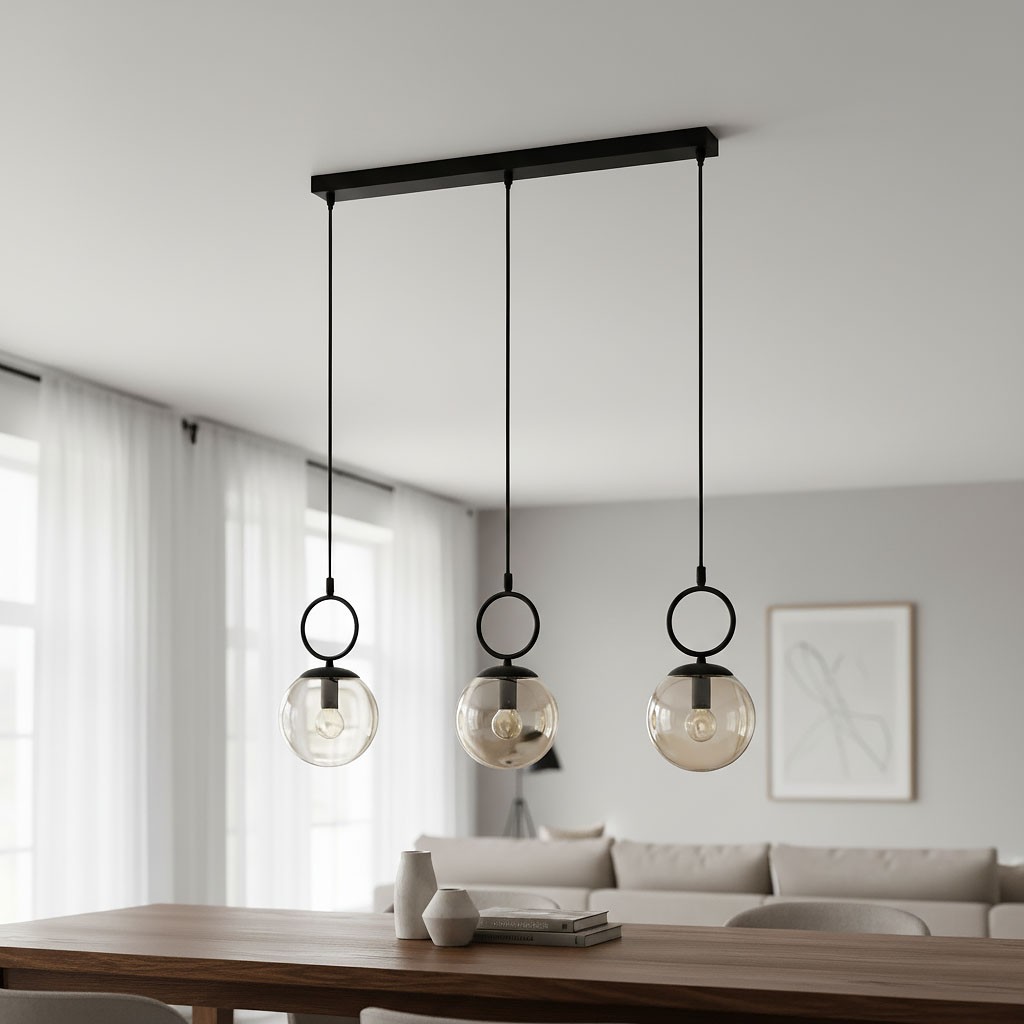 Lampa wisząca Sitro z listwą, trzy klosze E14 w czarnym kolorze z bursztynowymi szkłami. Produkt zawieszony na czarnych linkach, w nowoczesnej aranżacji wnętrza nad drewnianym stołem. Tło jasne, z dużymi oknami i minimalistycznym umeblowaniem.