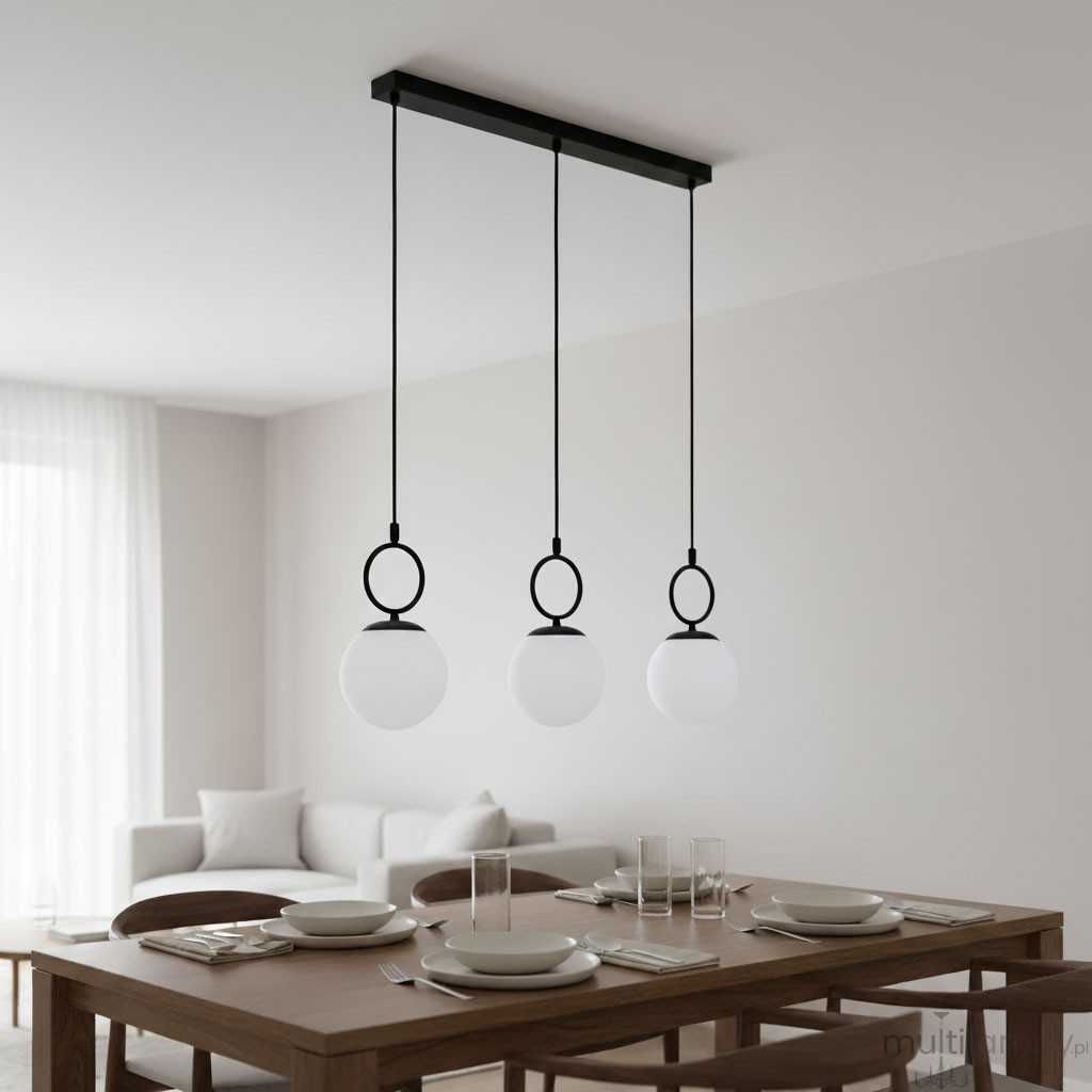 Lampa wisząca Sitro w kolorze czarnym i białym, z trzema okrągłymi kloszami z mlecznego szkła zawieszonymi na długich linkach. Ujęcie frontalne, lampy zamontowane na prostokątnej, czarnej listwie, w tle stół z nakryciem w nowoczesnym wnętrzu.