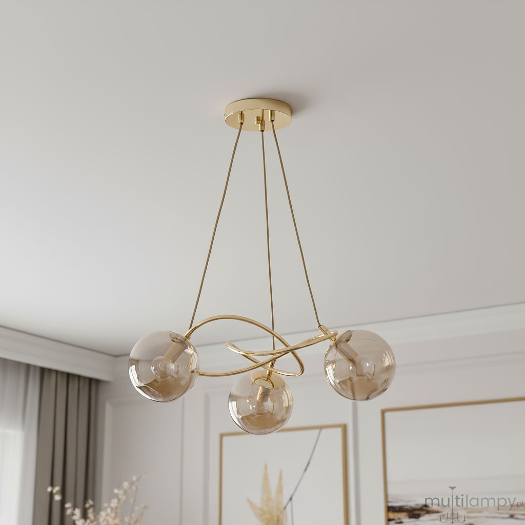 Lampa wisząca Velta 3-punktowa w kolorze złotym, z trzema przezroczystymi kloszami w kształcie kul. Produkt zawieszony na cienkich, złotych linkach z sufitu, tworzy nowoczesny akcent w aranżacji wnętrza.