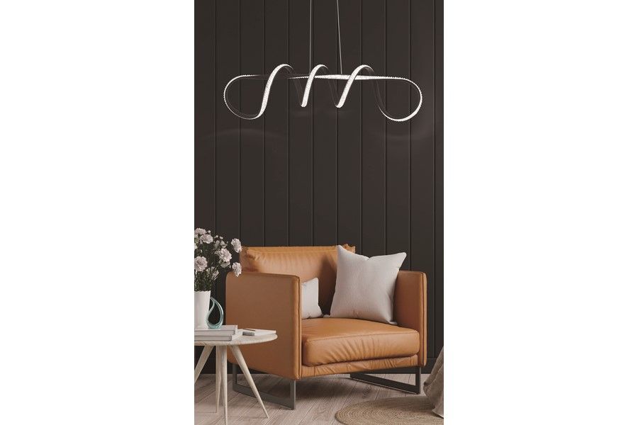 Lampa wisząca LED Vesper 40W CCT w kolorze czarnym, z unikalnym, falistym kształtem. Zawieszona nad brązowym fotelem, w jasnym wnętrzu z drewnianą podłogą i dekoracyjnym kwiatem w tle.